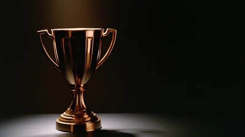 Gold championship trophy on dark surface under spotlight