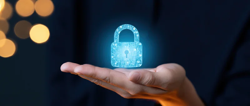 Hand holding glowing blue digital lock hologram against dark background with bokeh lights