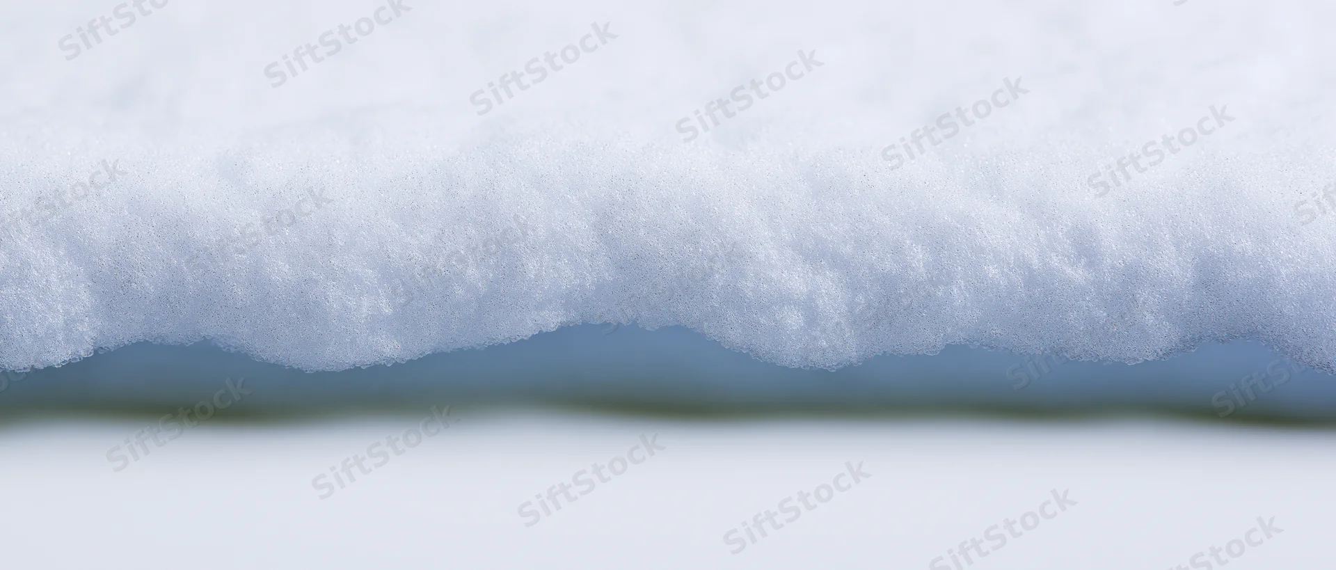 Closeup of a horizontal ridge of freshly packed snow against a blurred background