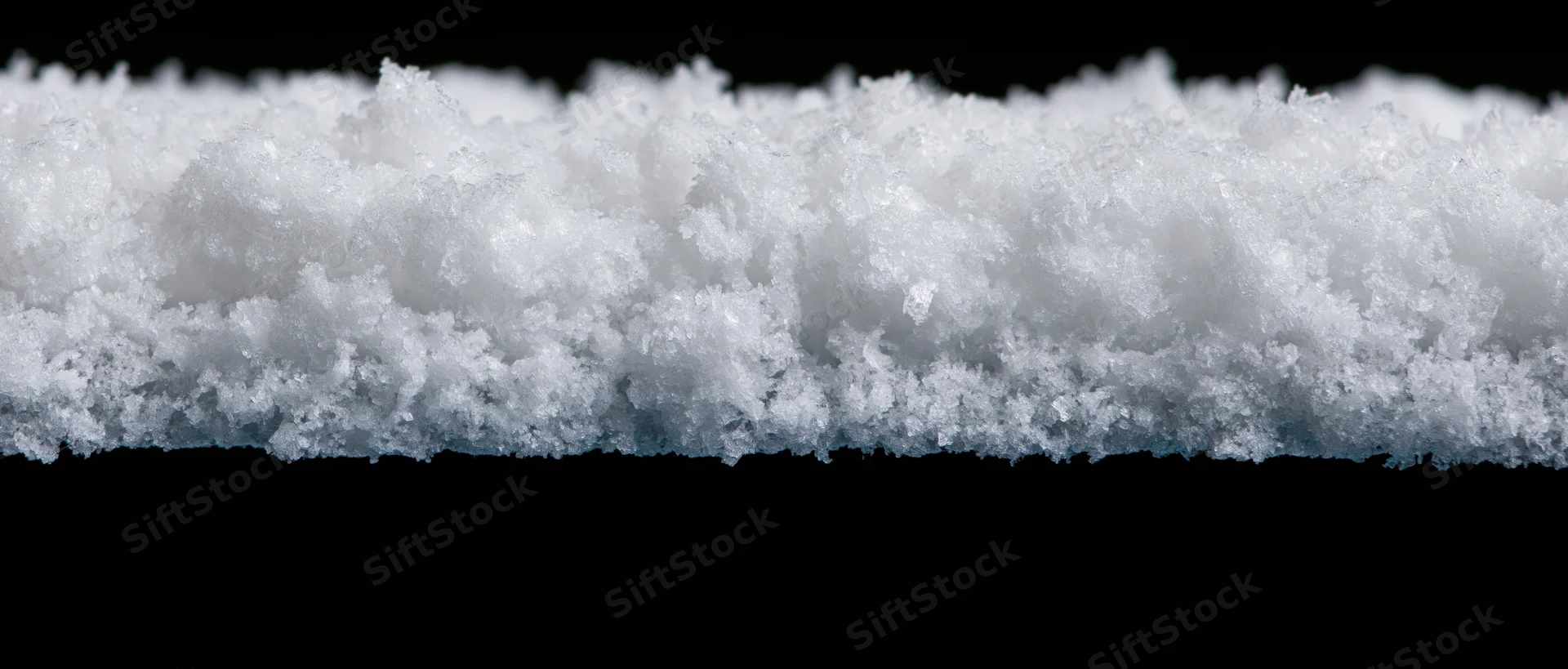 Horizontal strip of freshly accumulated snow isolated against black background