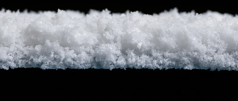 Horizontal strip of freshly accumulated snow isolated against black background