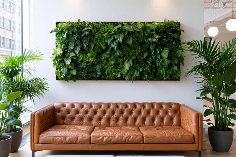 Living plant wall above a brown tufted leather sofa in a modern office interior