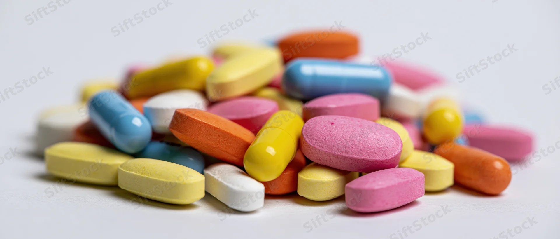 A pile of colorful pharmaceutical pills and capsules on a white surface