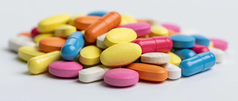 A pile of colorful pharmaceutical pills and capsules on a white surface