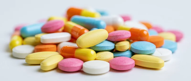 A pile of colorful pharmaceutical pills and capsules on a white surface