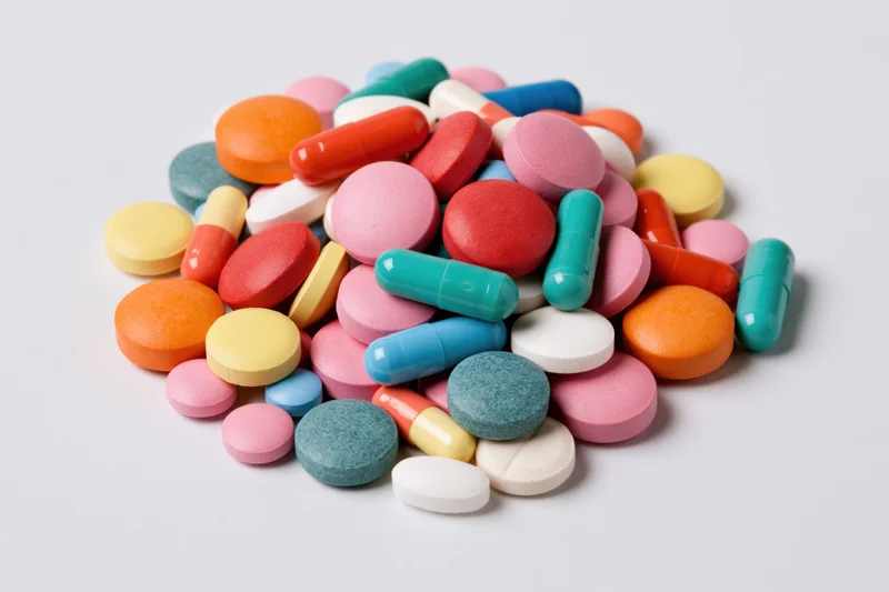 A pile of colorful pharmaceutical pills and capsules on a white surface