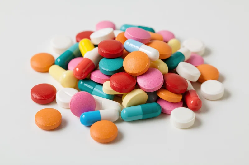 Assorted pharmaceutical pills and capsules piled on a white surface