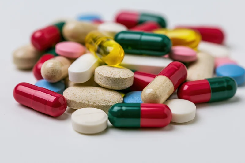Assorted pills and capsules scattered on a white surface