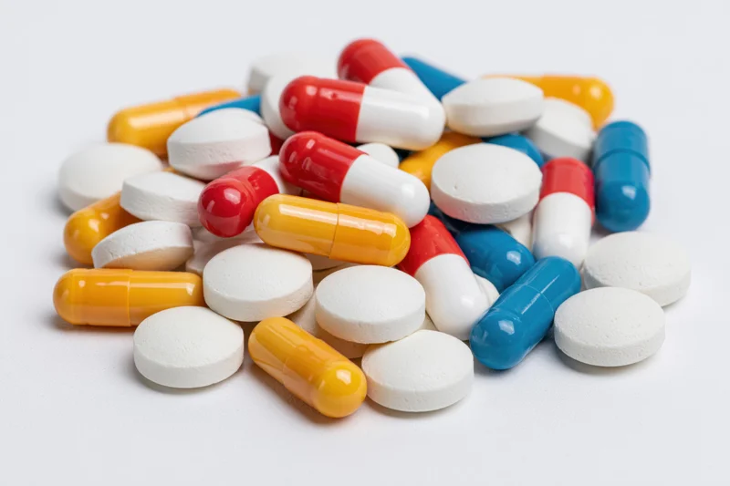 Assorted prescription pills and capsules piled on a white surface