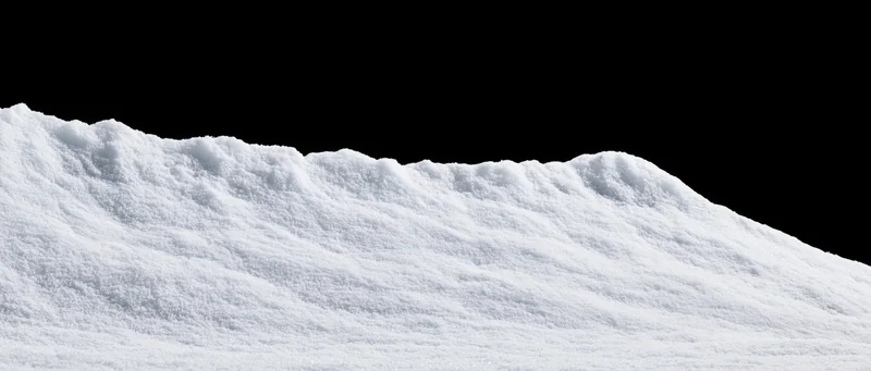 Low snow drift with gently uneven ridgeline against black background
