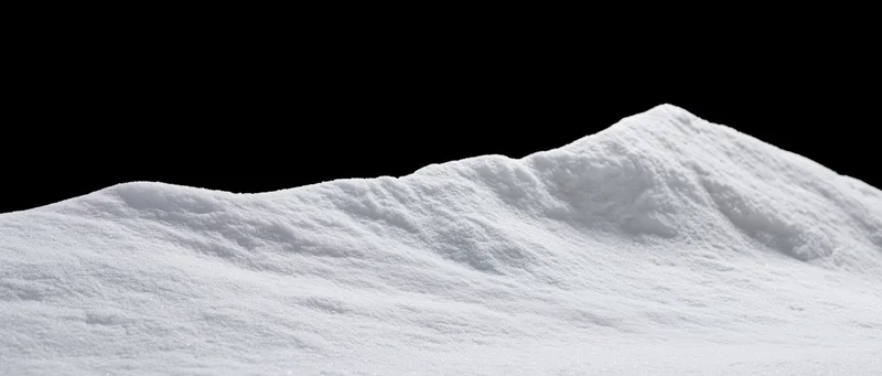 Low snow drift with gently uneven ridgeline against black background