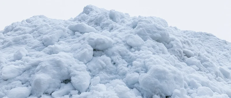 Close-up of a freshly piled snow mound under overcast sky