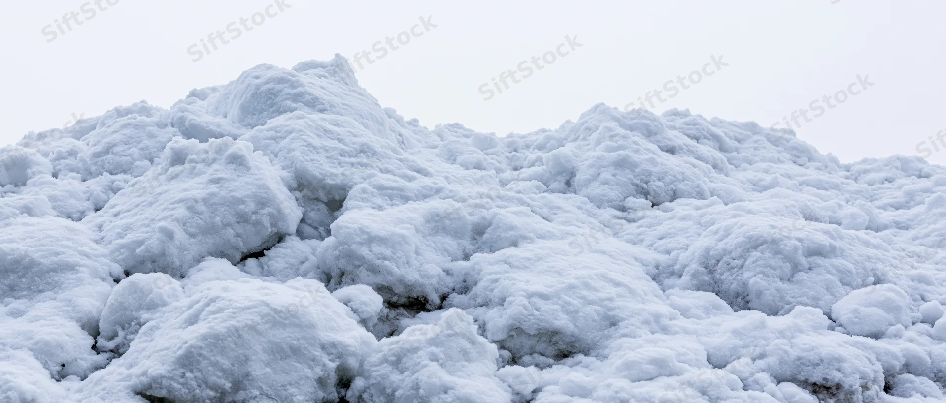 Close-up of a freshly piled snow mound under overcast sky