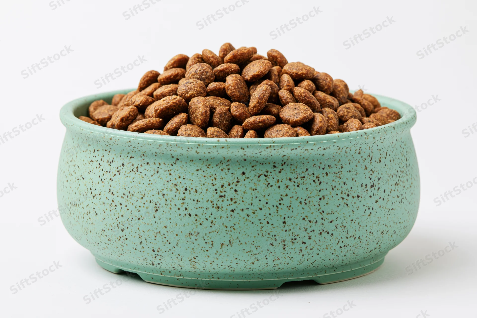 Mint green speckled ceramic pet bowl heaped with dry kibble on white background