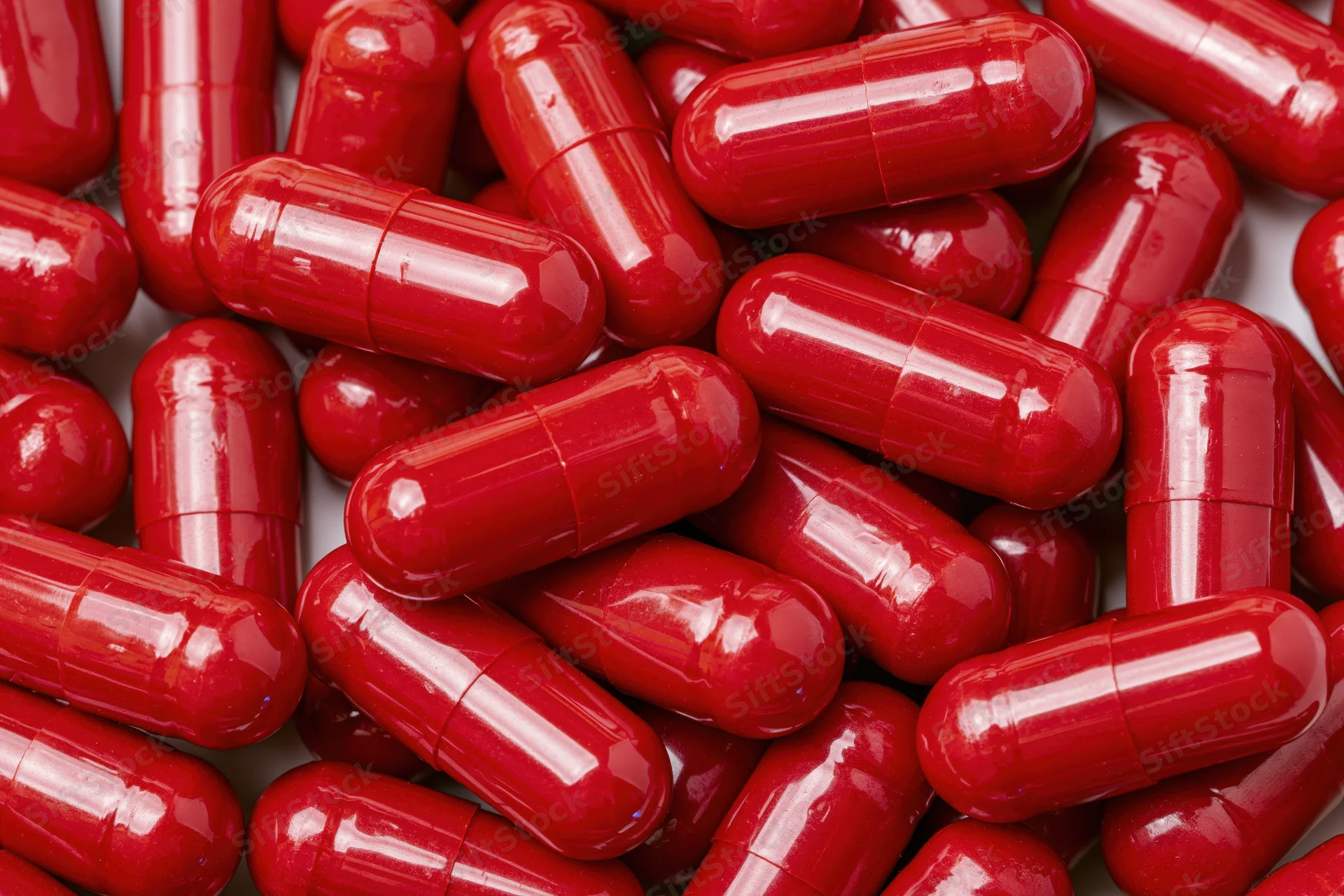 Bright red gelatin capsules scattered in a pile