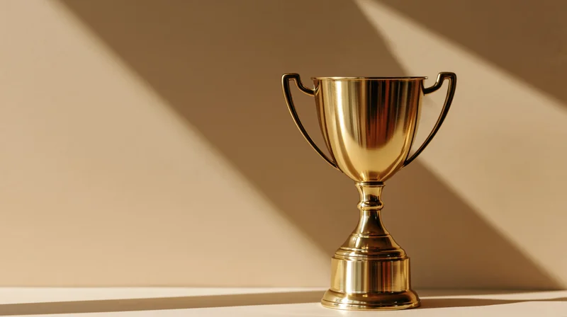Polished gold trophy cup on a flat surface with angular shadows