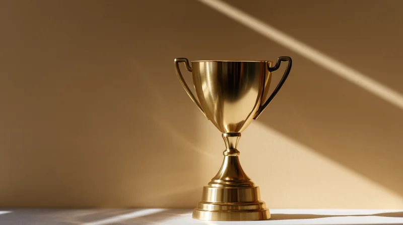 Polished gold trophy cup on flat surface with sunlight casting diagonal shadow