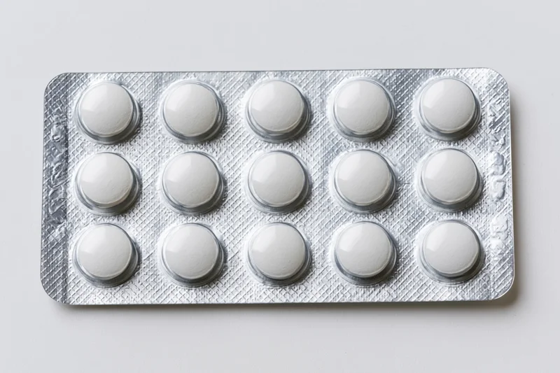 Fifteen white tablets in a silver aluminum blister pack on a white surface