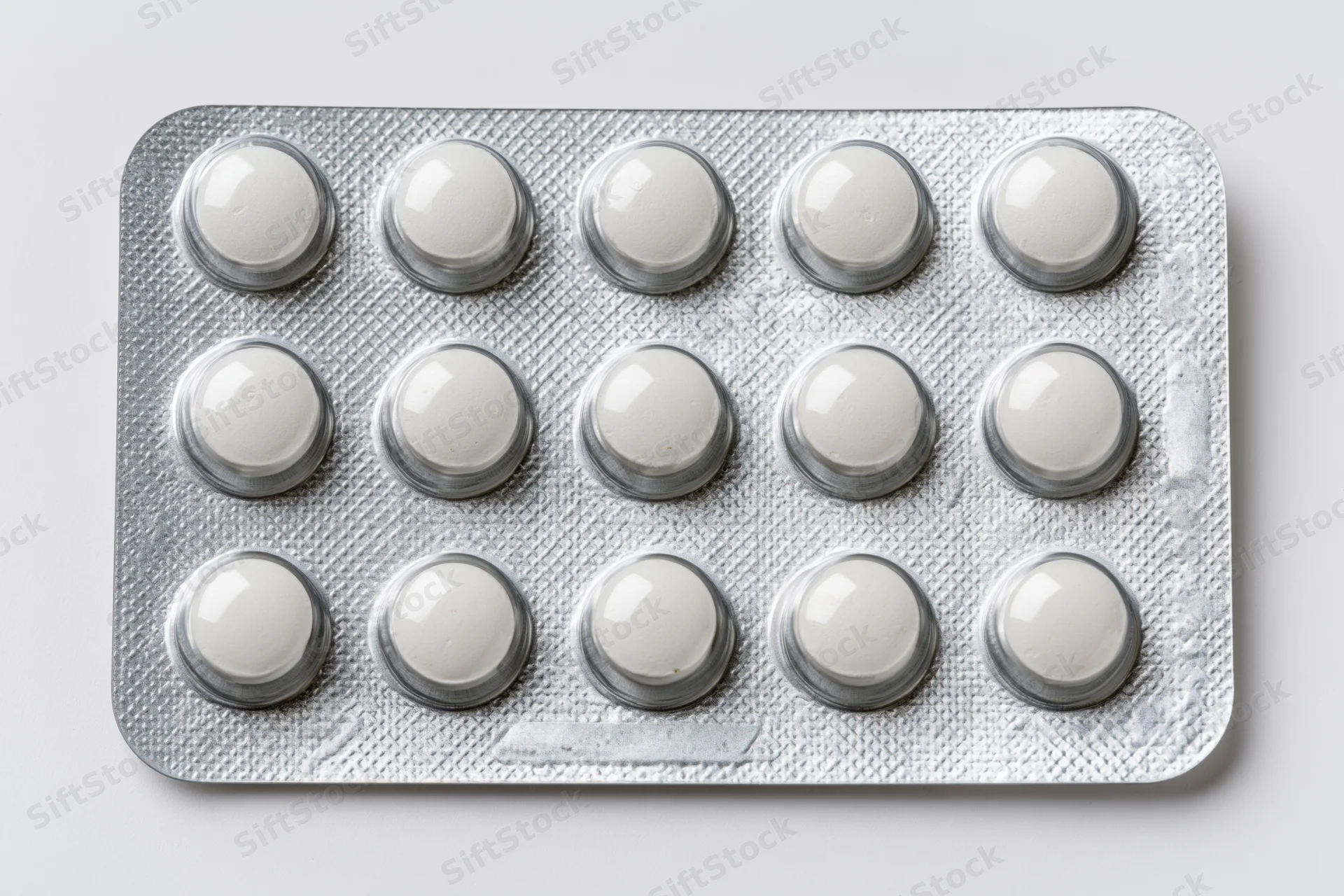 Fifteen round white pills in a silver aluminum blister pack on a plain white surface