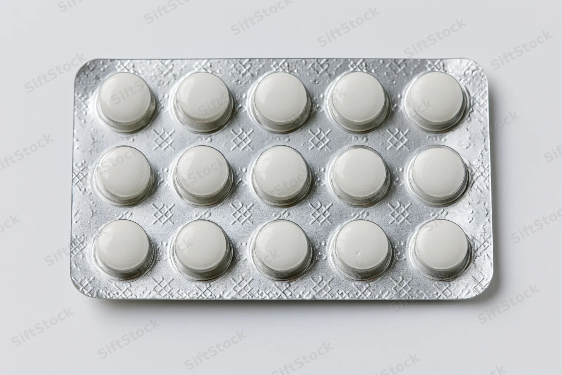 Silver aluminum blister pack with fifteen round white tablets on white background