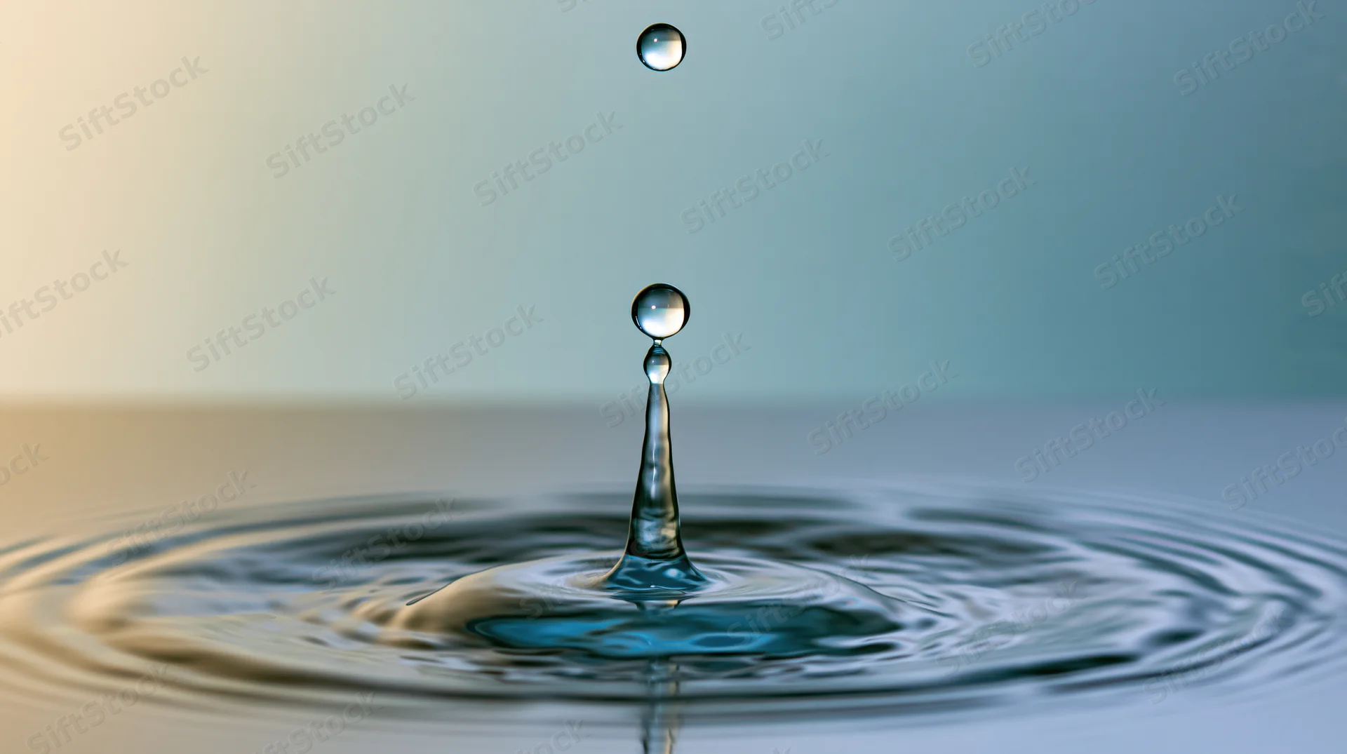 Water droplet mid-collision with calm surface creating ripples and splash
