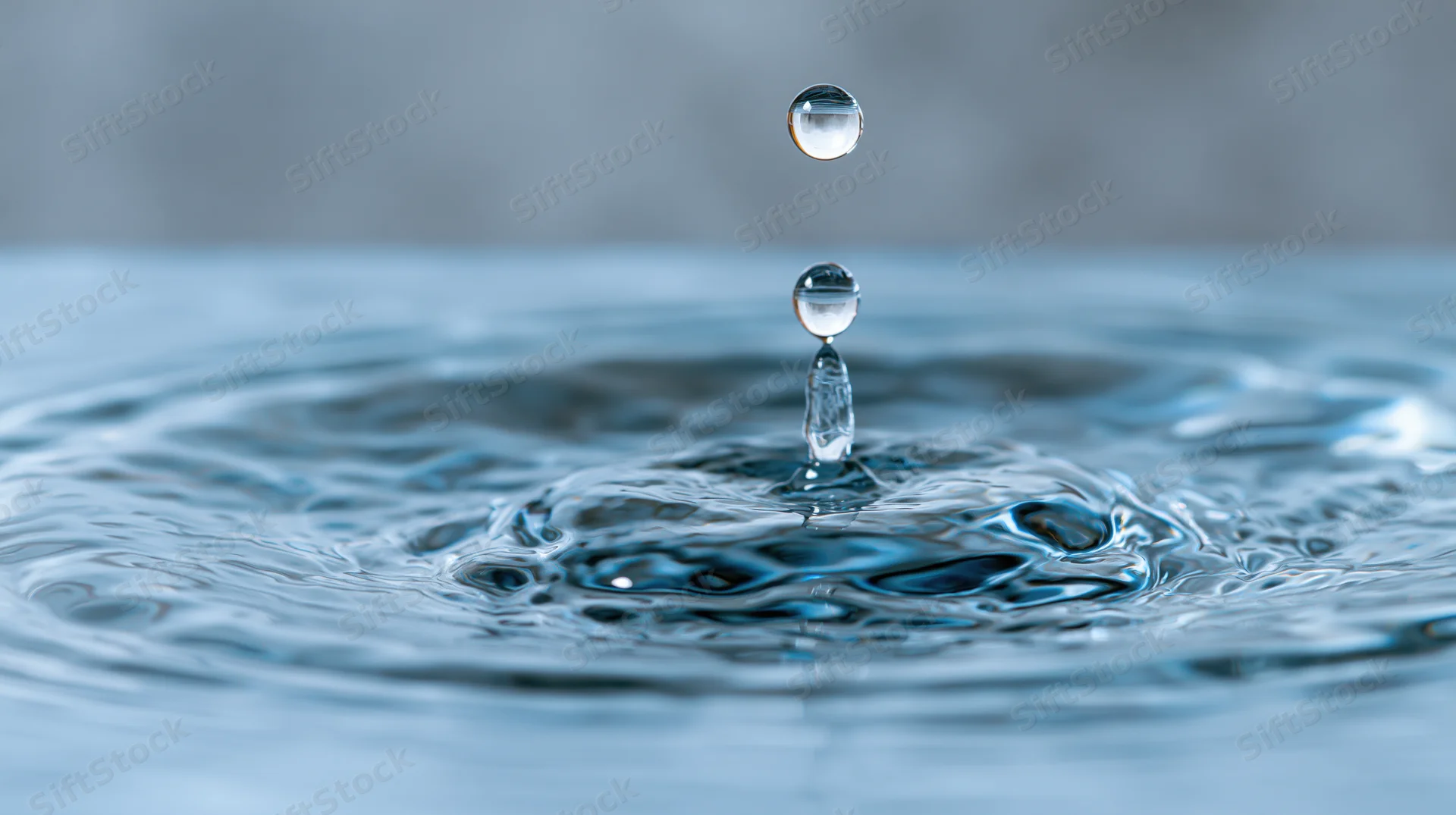 Water droplet suspended above a crown splash on a calm surface