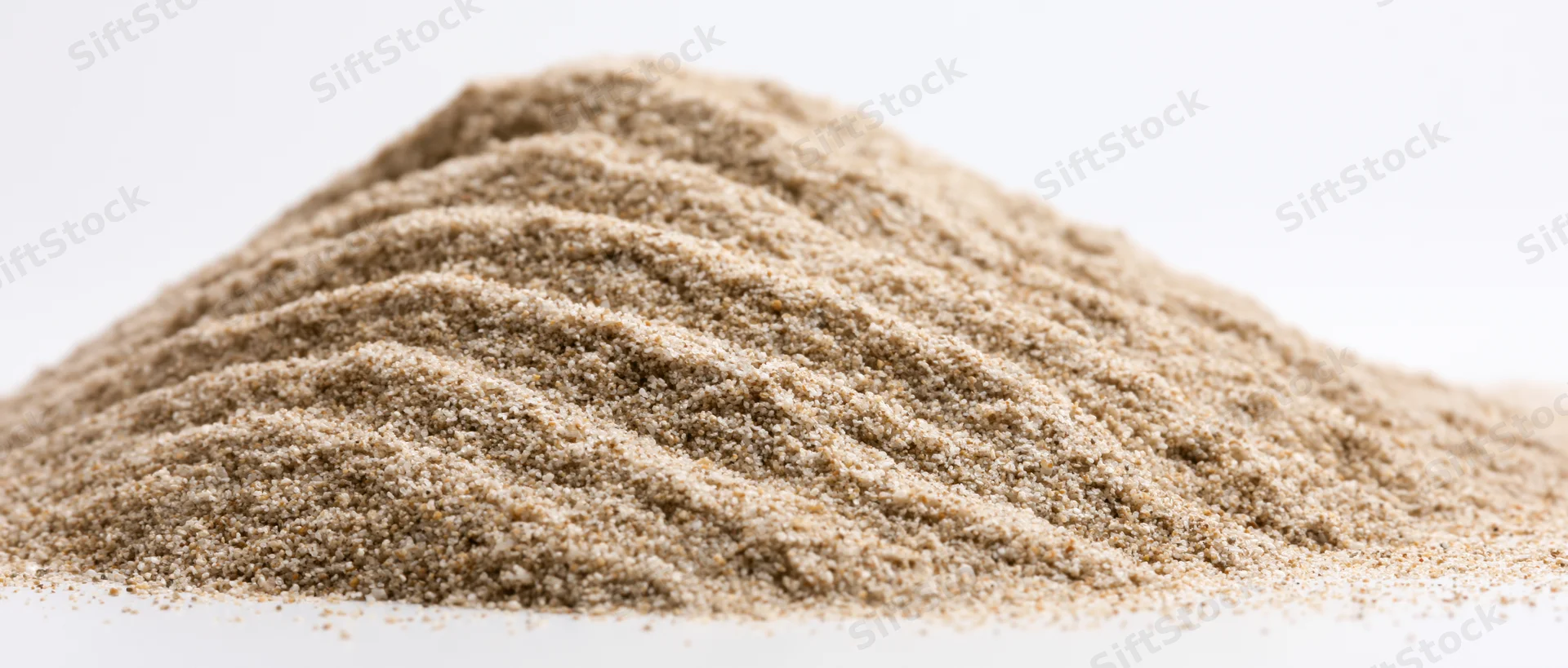 A mound of fine dry sand with rippled ridges on a white surface