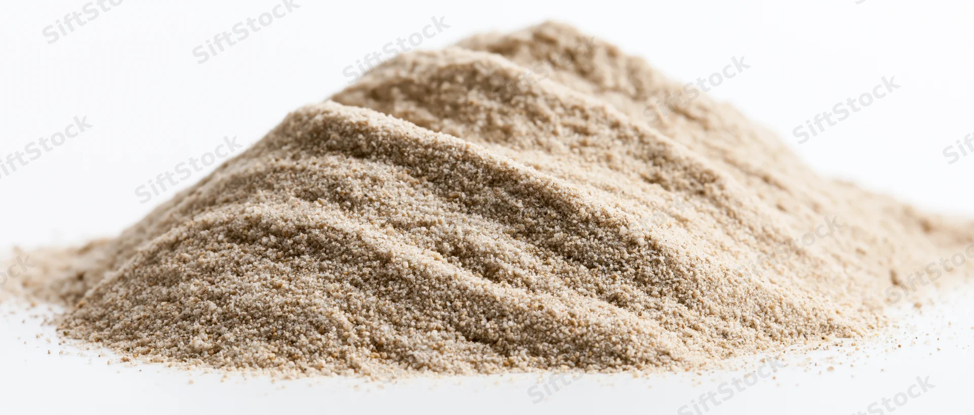 A small elongated pile of fine dry sand with soft rippled ridges on a white background