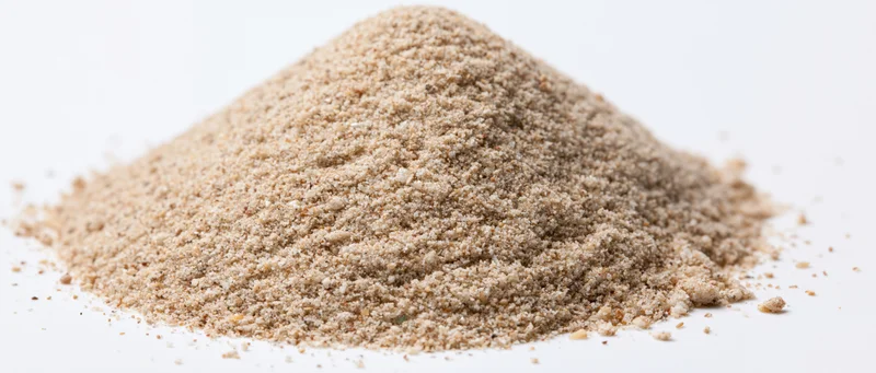 A mound of dry beach sand on a white surface