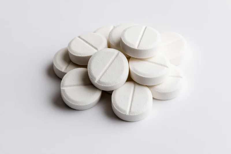 A small loose pile of round white pharmaceutical tablets on a plain white surface