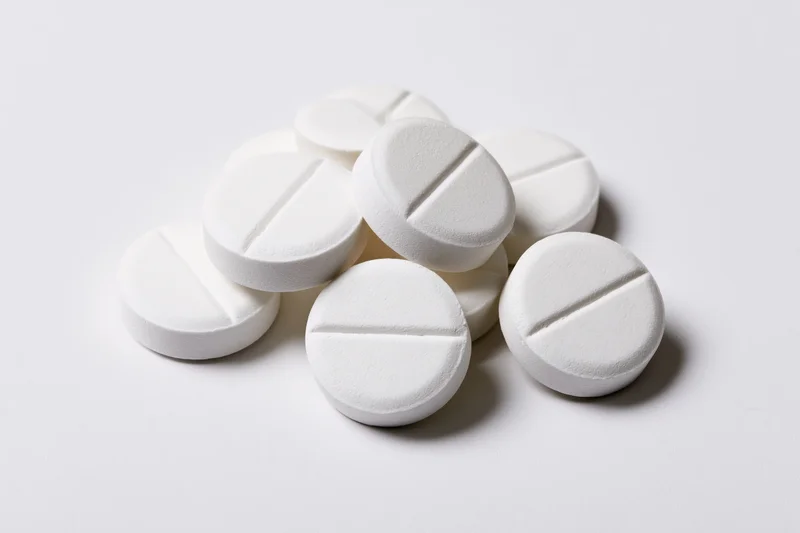 Round white pharmaceutical tablets piled loosely on a plain white surface