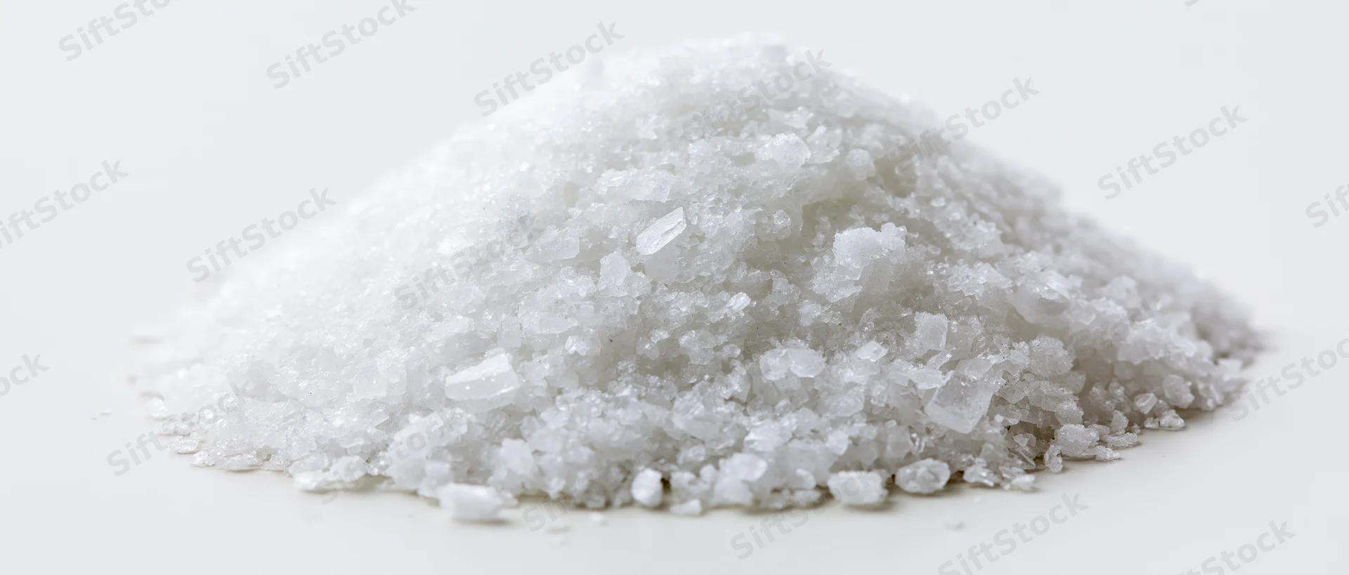 A mound of coarse white crystalline salt on a plain white surface