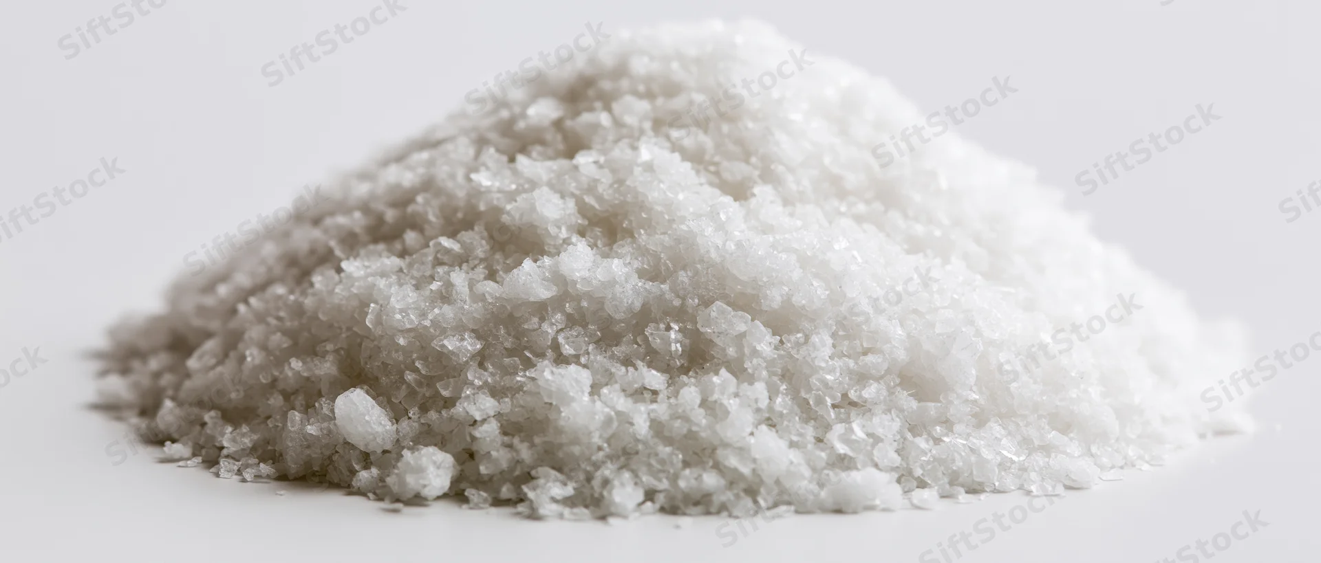 A mound of coarse white crystalline salt on a plain white surface