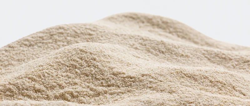 Closeup of a mound of dry beach sand with gently undulating surface against white background
