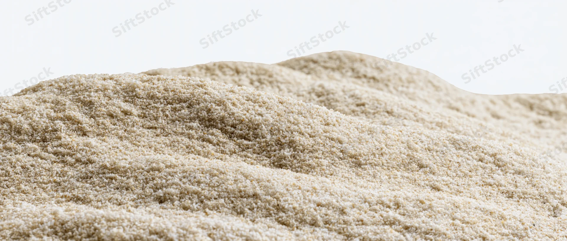 Mound of dry beach sand with gently undulating surface against white background