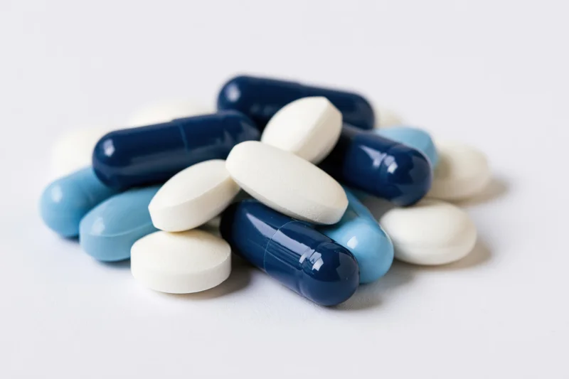 Assorted pharmaceutical pills and capsules piled on a white surface