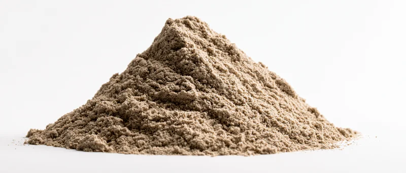 A mound of dry desert sand with natural ridges and peaks on a white surface