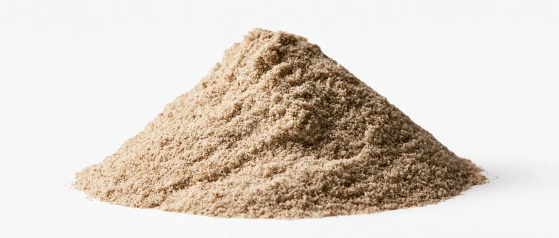 A small pile of dry desert sand with natural ridges and peaks on a white background