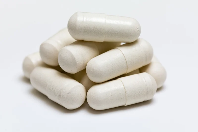 Off-white gelatin supplement capsules stacked in a small pile on a white background