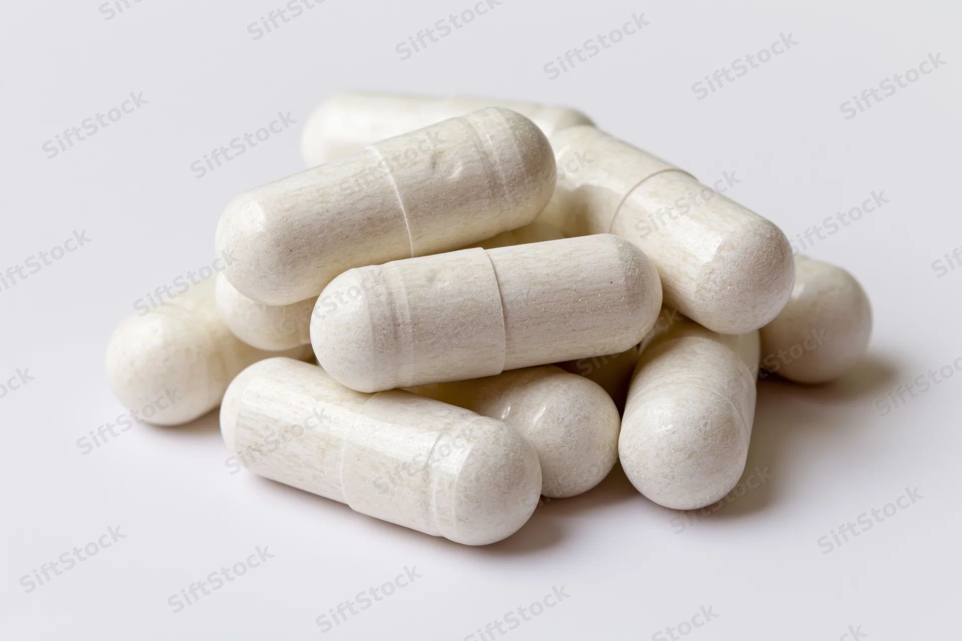 Off-white gelatin supplement capsules stacked in a small pile on a white surface