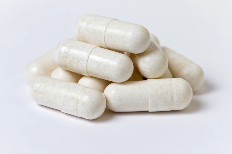 Off-white gelatin supplement capsules stacked in a small pile on a white surface