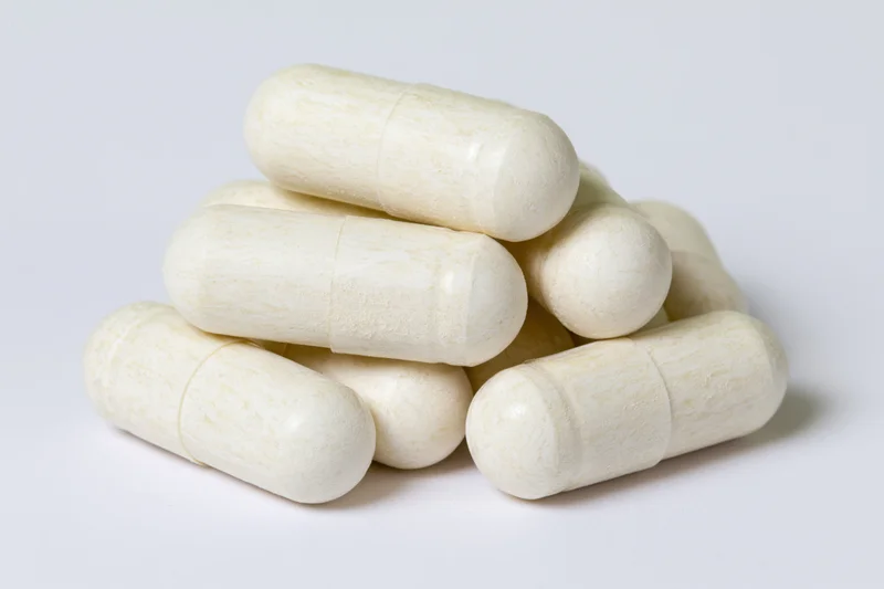 Off-white gelatin supplement capsules stacked in a small pile on a white surface