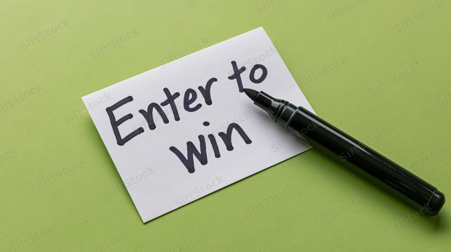 Handwritten note reading enter to win with black marker on green surface