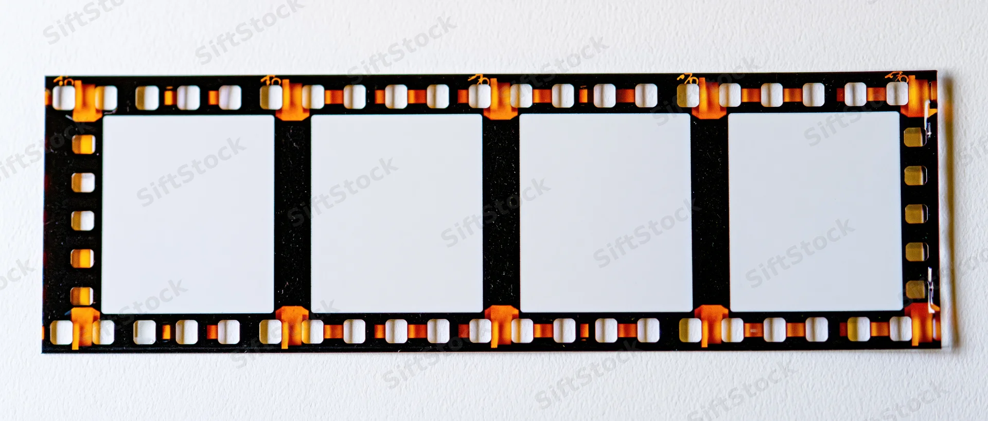Blank 35mm film strip with four empty frames laid flat on white surface