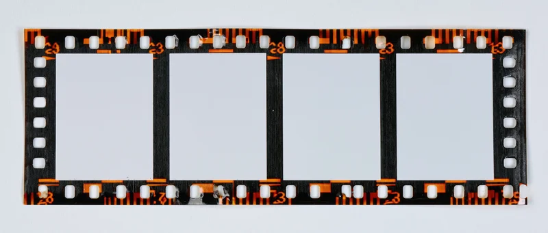 Blank 35mm film strip with four empty frames laid flat on white background