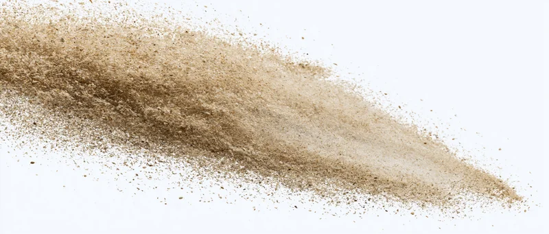 Airborne sand particles scattered mid-flight against white background