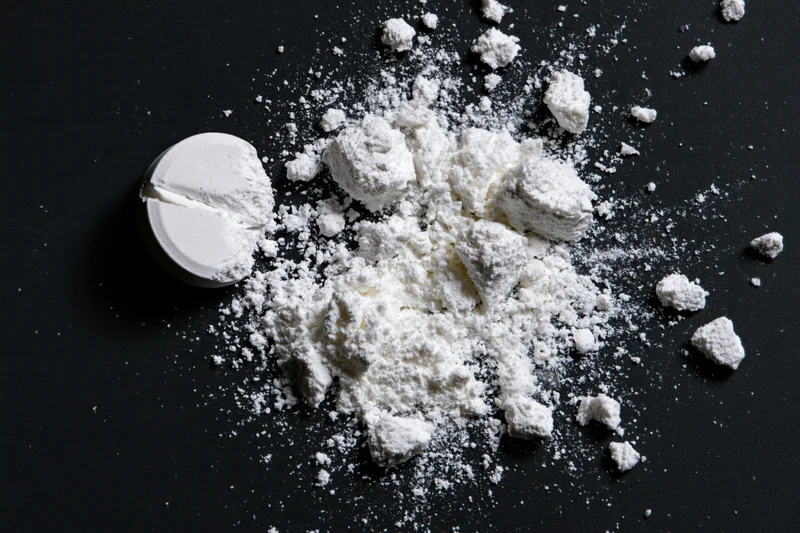 Crushed white pharmaceutical tablet scattered as powder on black surface