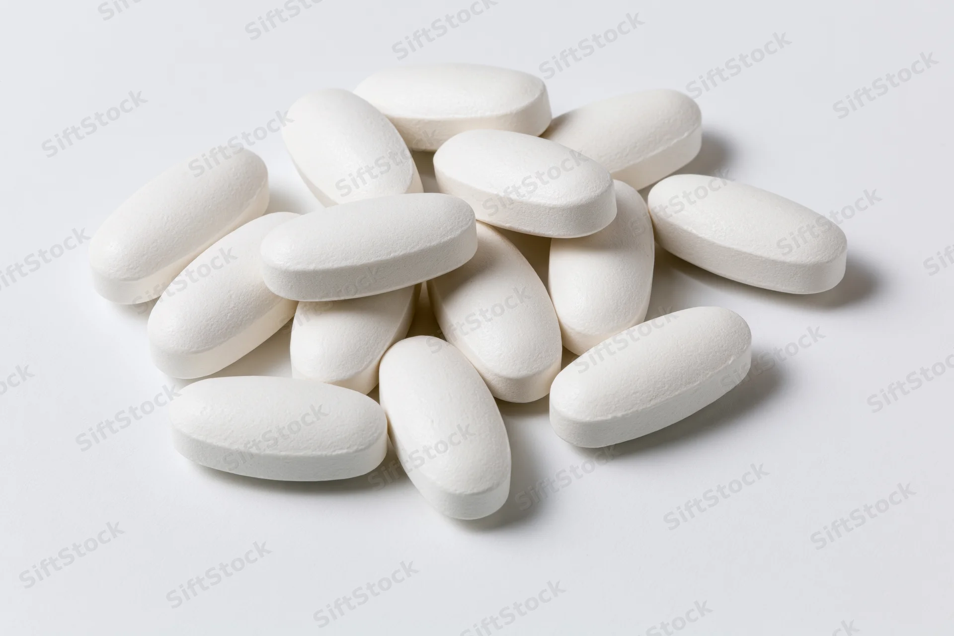 White oval coated tablets scattered on a plain white surface