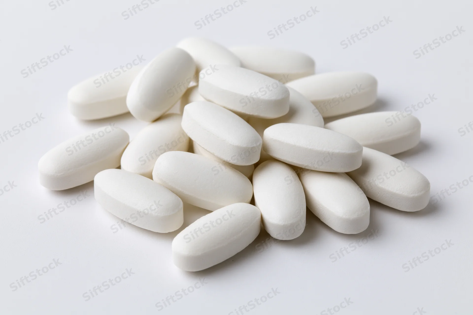 White oval coated tablets scattered on a plain white surface