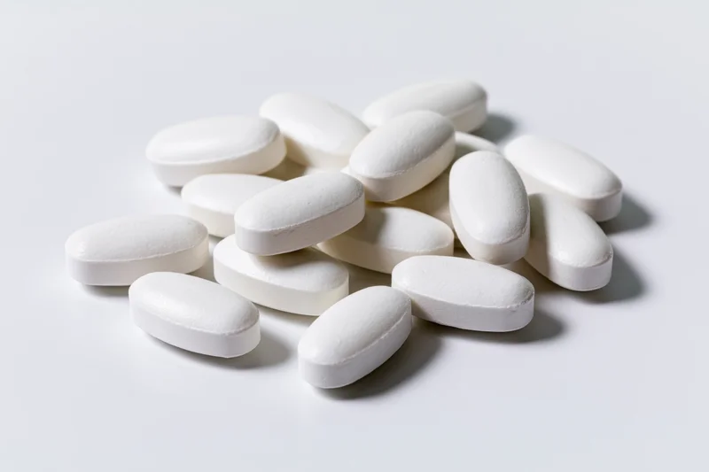 White oval coated tablets scattered on a plain white surface